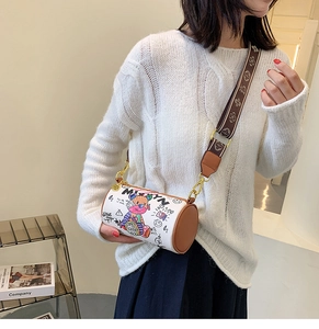 Détail d'un sac cylindrique blanc avec graffitis d'ours et bandoulière à logo