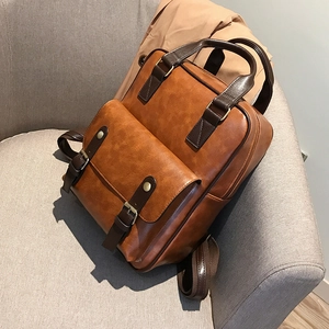 Detail of vintage brown leather backpack with buckle on grey fabric sofa background