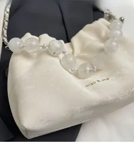 Detail of off-white pleated drawstring bag with beaded handle and gold miao & she logo