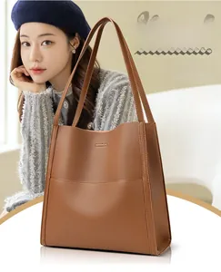 Close-up of brown litchi grain leather texture on minimalist tote bag with thin straps