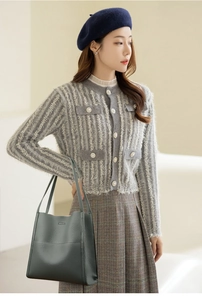 Detail showing an elegant dark green leather tote bag with a grey knit cardigan and skirt