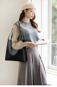 Close-up of a black leather tote bag featuring a high-quality lychee texture and shoulder strap