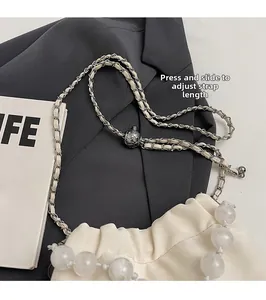 Detail of adjustable metal buckle and beaded chain on a white ruched satin bag