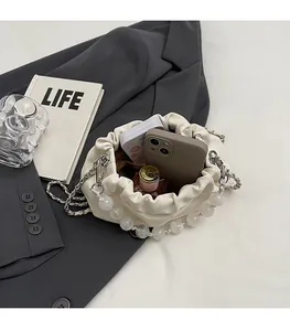 Detail of cream pleated crossbody bag showing spacious interior with phone and cosmetics