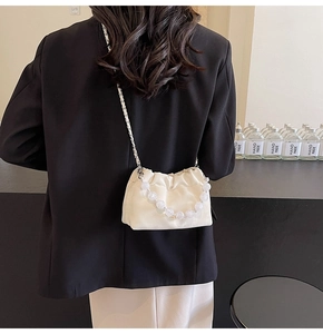 Detail view of cream pleated cloud bag with elegant pearl strap and metal chain strap