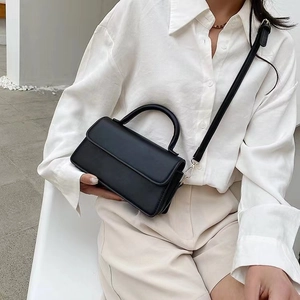 Chic black minimalist square crossbody bag styled with a white shirt and beige trousers