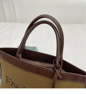Detail of canvas tote bag showing dark leather handle stitching and Fri print