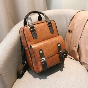 Brown vintage faux leather backpack with front buckles placed on a sofa for a stylish look