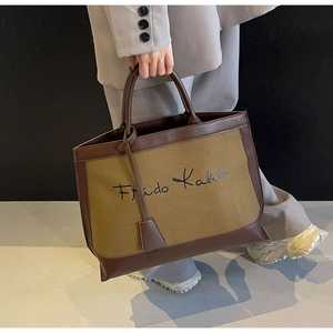 Detailed view of canvas tote bag featuring Frida Kahlo print and brown leather handles