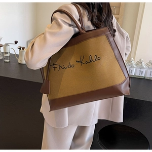 Detail of canvas tote bag with Frida Kahlo signature and brown leather trim on model