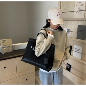 Close-up of black canvas tote bag with white script embroidery in a casual lifestyle setting
