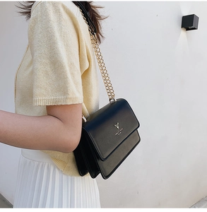 Detail view of a black leather chain crossbody bag with golden deer logo on the flap