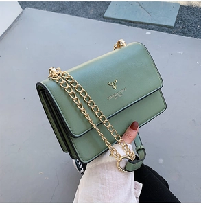 Detail of sage green leather bag with gold metal chain and deer logo ornament