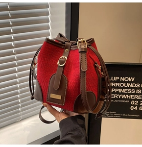 Detail of red tweed bucket bag with brown leather trim and drawstring closure