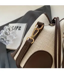 Detailed close-up of golden metal clasp and dark leather piping on woven canvas bucket bag