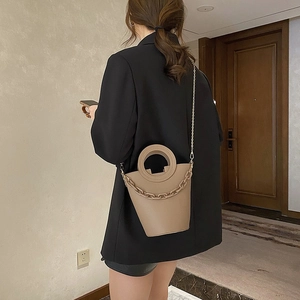 Detail of tan leather bucket bag with resin chain and circular handle shown on model