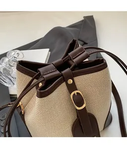 Detail of fabric and brown leather bucket bag with drawstring closure and metal buckle
