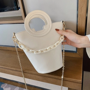 Detail of white PU bucket bag featuring a round hollow handle and white acrylic chain