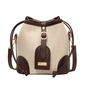 Minimalist canvas bucket bag with brown leather trim and polished gold hardware detail
