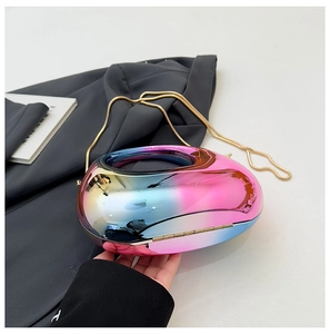 Macro detail of iridescent oval evening clutch featuring a metallic finish and gold chain