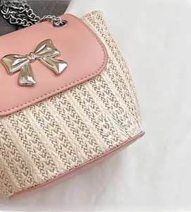 Gros plan sur le tissage beige avec rabat en cuir rose et nœud argenté d'un mini sac