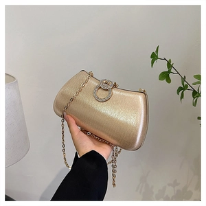 Close-up of champagne gold evening clutch featuring a sparkling rhinestone ring clasp and chain
