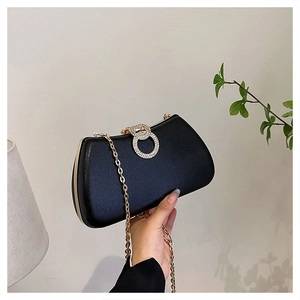 Detail of black evening bag featuring sparkling rhinestone rings and gold chain strap