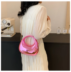 Metallic pink semi-circular handbag with gold chain strap styled on a white dress
