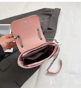 Détail intérieur du sac en cuir rose avec chaîne argentée, compartiments et poche zippée