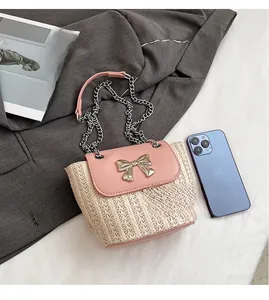 Détail du sac seau tissé avec rabat en cuir rose et boucle nœud en métal sur tissu tailleur