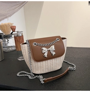 Détail d'un sac bandoulière tissé avec rabat en cuir et boucle noeud argentée