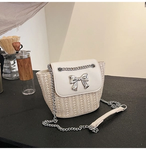 Vue détaillée d'un sac à bandoulière tissé crème avec nœud argenté et bandoulière chaîne