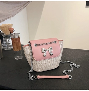 Détail du rabat en cuir rose avec nœud argenté sur un sac bandoulière tissé chic