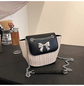 Détail du sac bandoulière en paille tressée et cuir noir avec nœud argenté