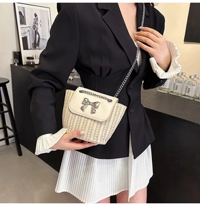 Détail du sac bandoulière en paille avec rabat en cuir blanc et fermoir nœud argenté
