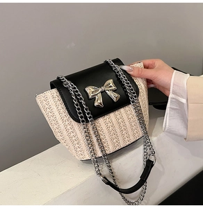 Détail du sac en paille tressée avec rabat en cuir noir et nœud en métal argenté