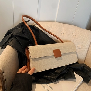 Detail einer minimalistischen Schultertasche aus strukturiertem Stoff mit Lederakzent