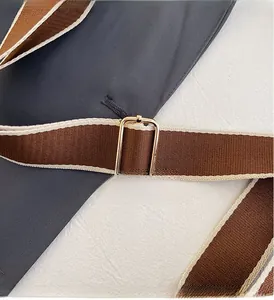 Close-up of golden metal adjustment buckle on striped woven shoulder strap for bags