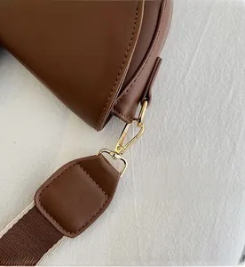 Close-up of golden metal hook and reinforced stitching on the brown leather strap