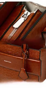 Detail of vintage brown leather bag featuring smooth zipper and silver logo plaque
