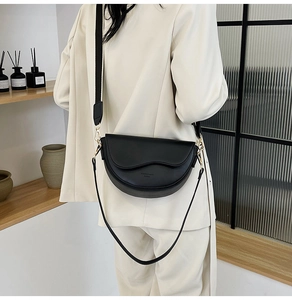 Detail of black semi-circle saddle bag with wavy flap design and gold hardware