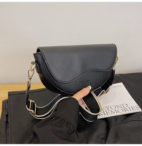 Detail of black saddle bag with wide shoulder strap and premium gold hardware