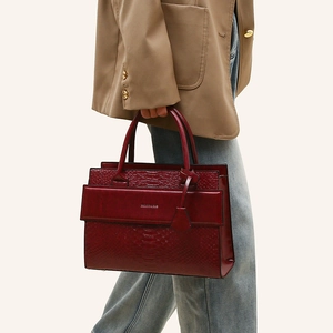 Close-up of deep red faux snake texture handbag with metal logo and dual handles