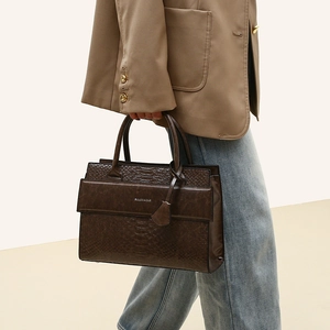 Detailed side view of dark brown tote bag with crocodile texture and metal logo
