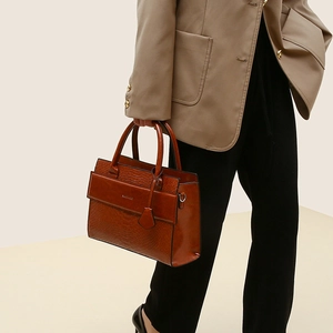Structured caramel handbag with crocodile pattern shown from a side view by a model