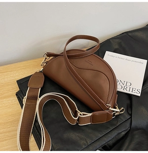 Detail view of brown matte PU saddle bag with wide woven strap and golden hardware