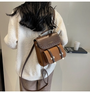 Detailed view of vintage two-tone brown leather backpack with contrast stitching on model