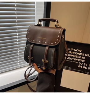 Detail of contrast leather backpack with white stitching and metal lock on top handle