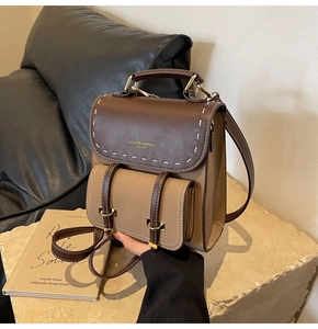 Detail of retro contrasting faux leather backpack with stitching and golden logo
