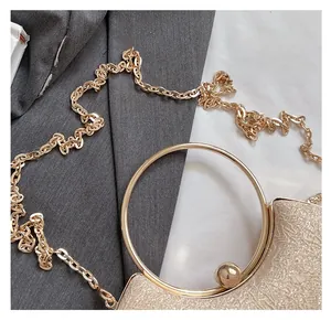 Detail of glitter evening bag with gold ring handle and metallic chain strap texture
